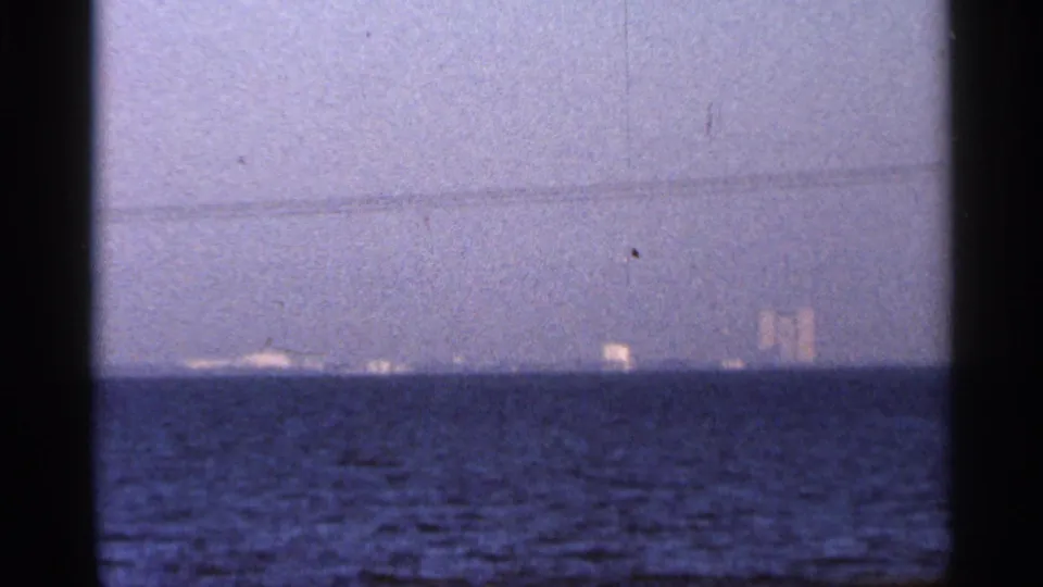 1966 Florida 8mm view across blue water toward small distant lights or shoreline forms at twilight.