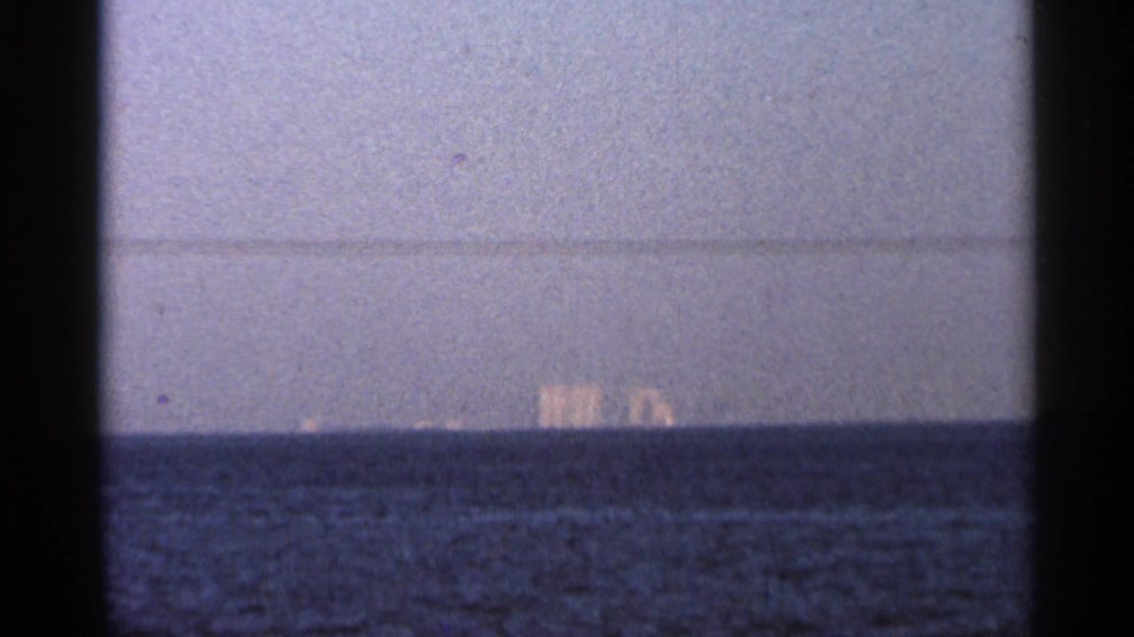 Distant buildings across open water beneath a pale sky.