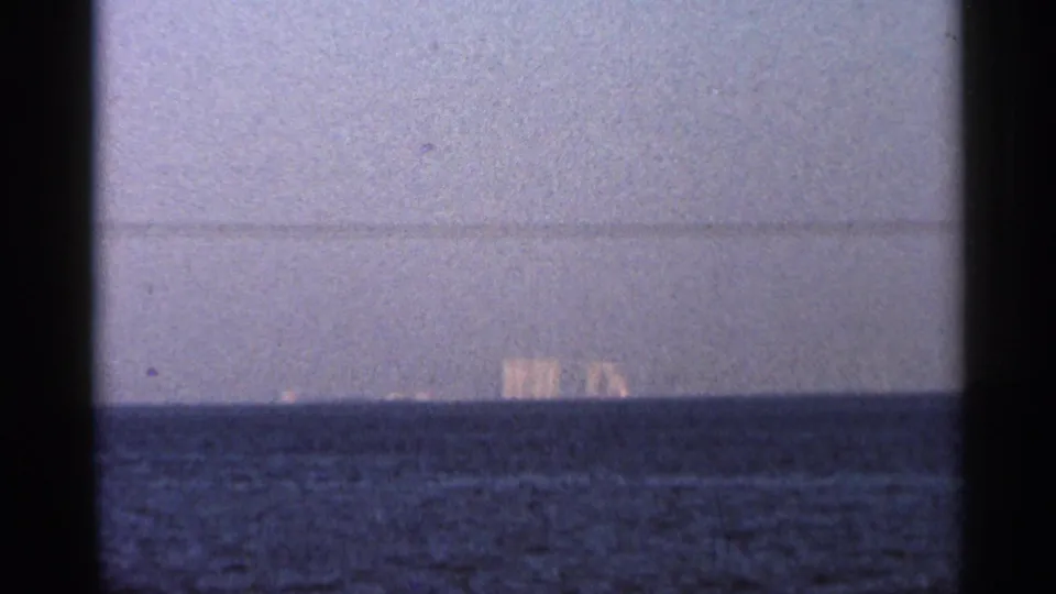 1966 Florida 8mm frame showing open water and faint distant buildings on the horizon.