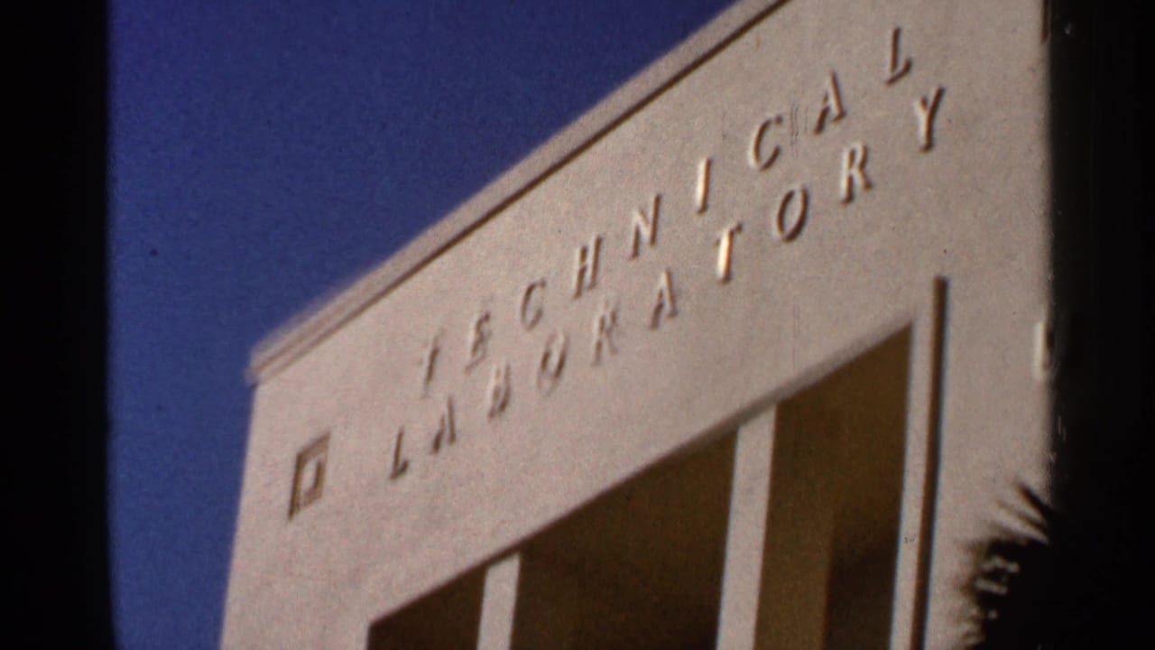 1966 Florida 8mm frame showing a Technical Laboratory facade with raised lettering, filmed from a low visitor angle.