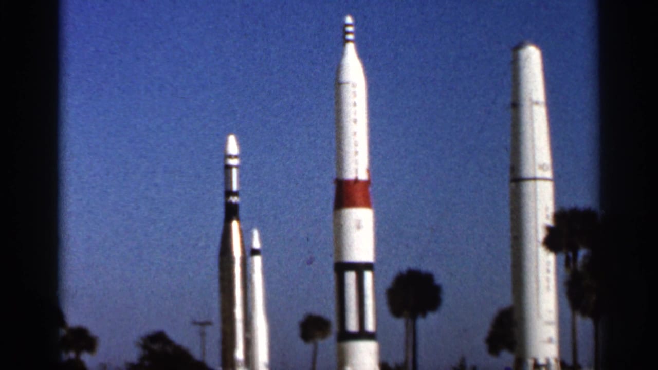 Tall display rockets stand against a blue sky with palm trees nearby.