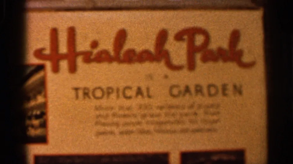 Close 1966 Florida frame of the Hialeah Park Tropical Garden sign, partially soft and framed by dark 8mm film edges.