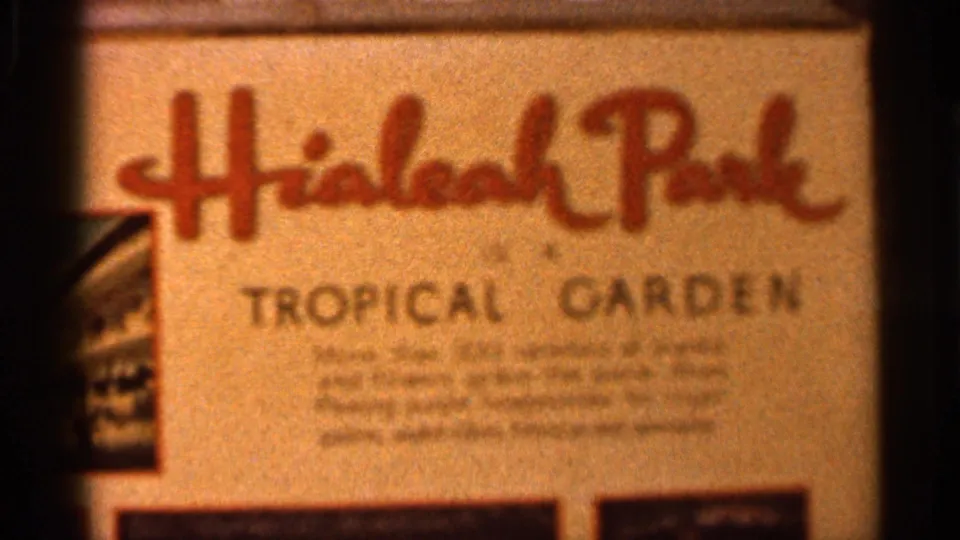 1966 Florida home-movie frame centered on the Hialeah Park Tropical Garden sign, with small text softened by focus and film grain.
