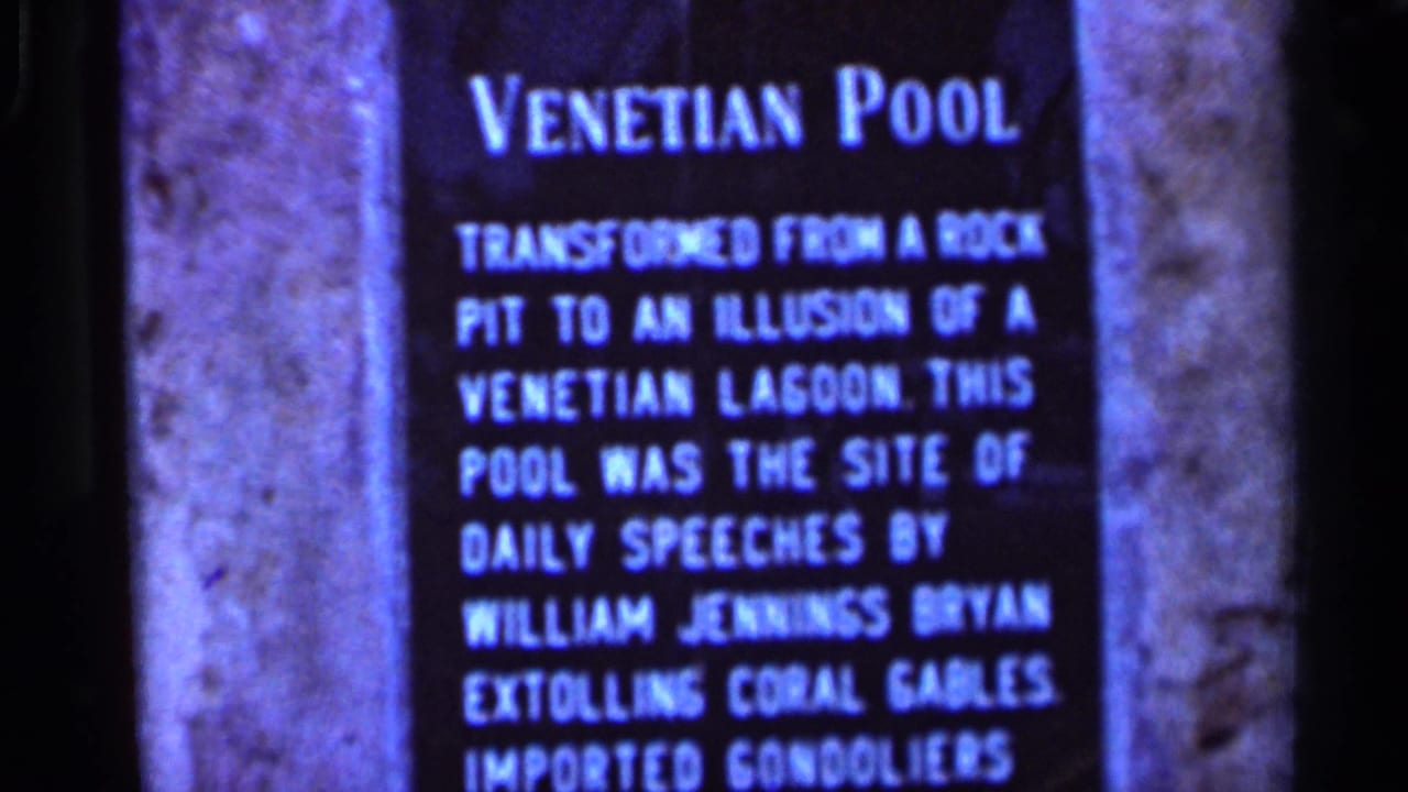 Venetian Pool sign beside a dark stone border, with white lettering on a blue panel.