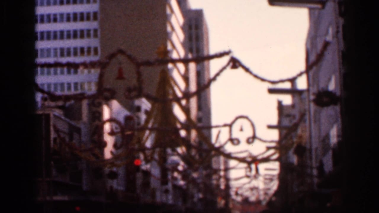 Downtown street with overhead holiday decorations between buildings.