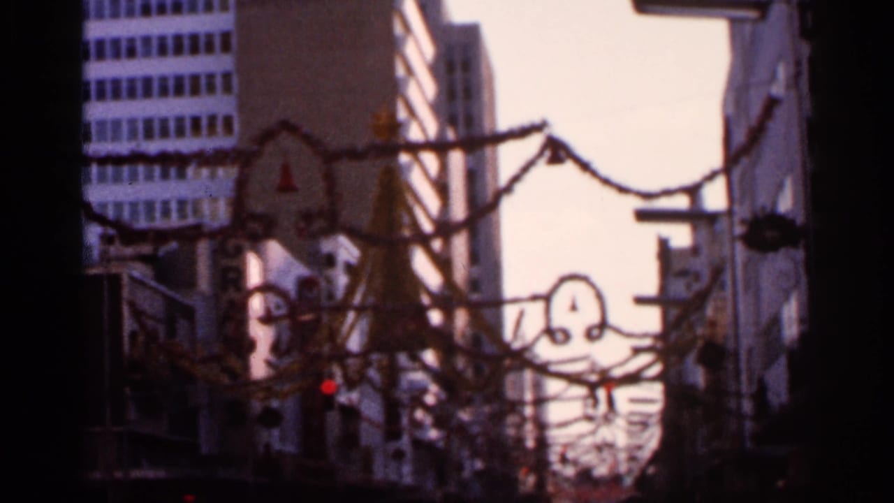 1966 Florida 8mm frame showing a soft, handheld downtown view with garlands and street fixtures overhead.