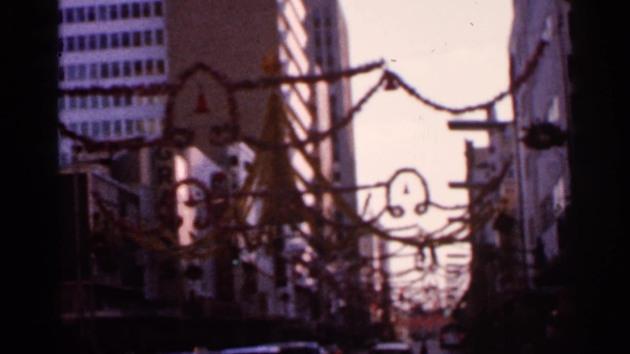 Street scene with overhead decorations, buildings, and soft 8mm exposure.