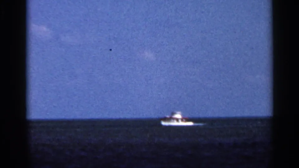 1966 Florida coastal home-movie view of a small white boat on open water under a broad blue sky.
