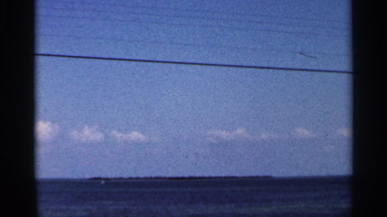 Blue ocean horizon under pale sky with low clouds and dark frame borders.