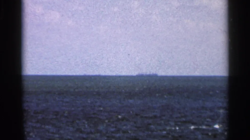 1966 Florida coastal frame with textured ocean water, pale sky, faint clouds, and a distant horizon.
