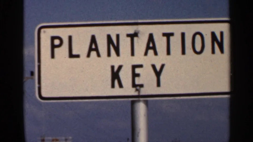 Close 1966 Florida view of the Plantation Key sign, cropped by the film frame with blue sky behind it.