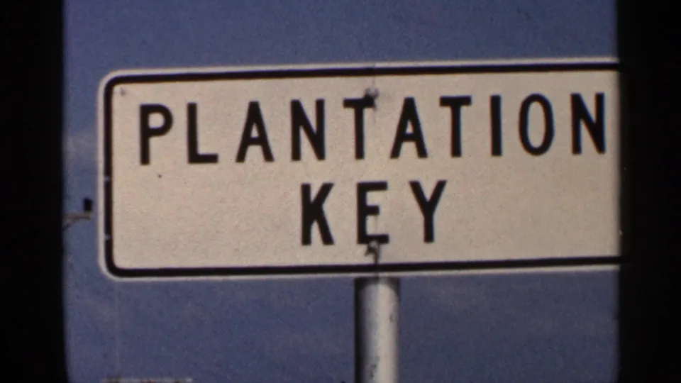 Final 1966 Florida frame showing the Plantation Key sign cropped tightly, with bold black lettering and sky behind it.