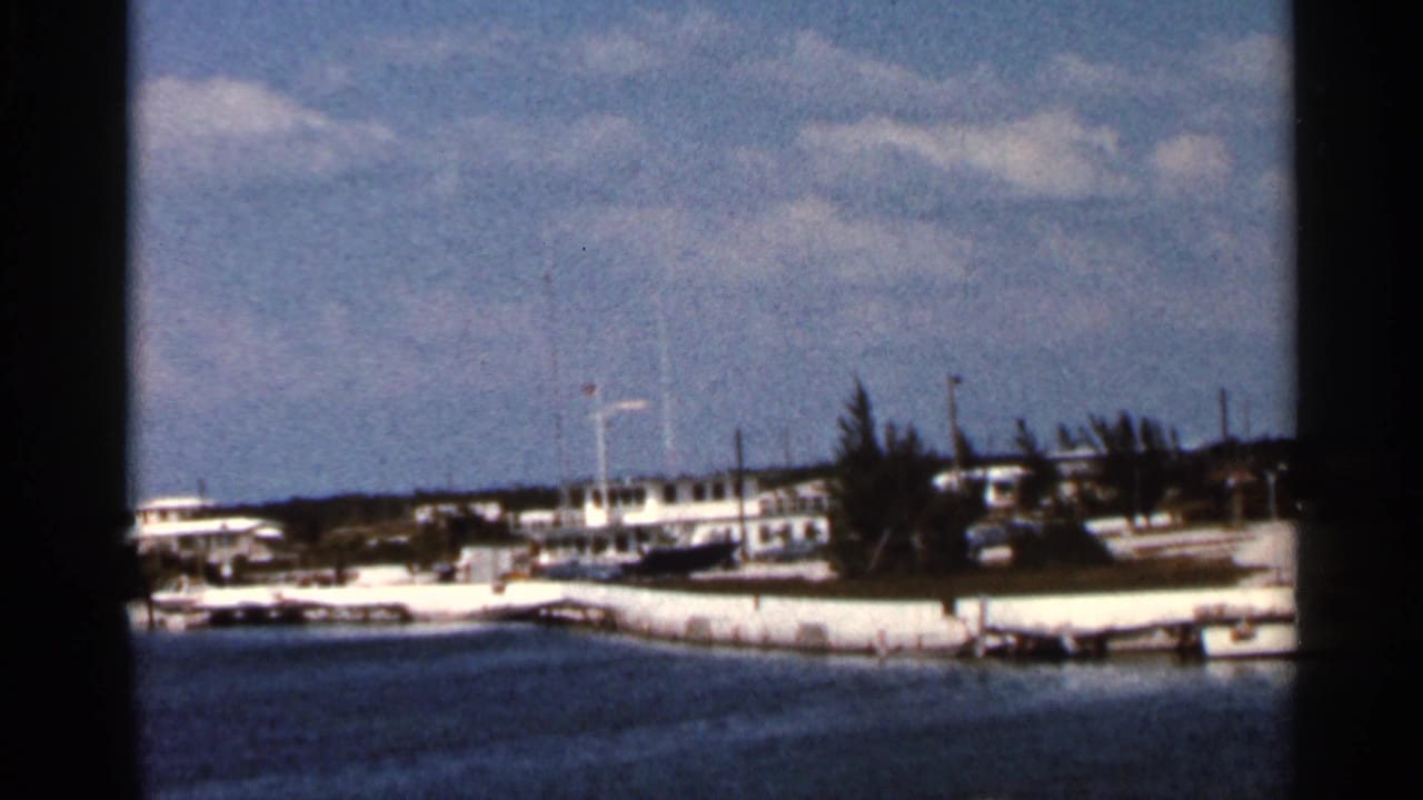Waterfront buildings and moored boats seen across a calm body of water.