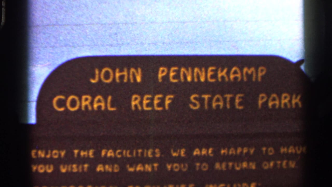 Close view of the John Pennekamp Coral Reef State Park sign with soft focus and yellow text.