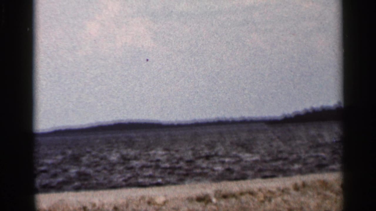 Rippling water beneath a bright sky with a low distant shoreline.
