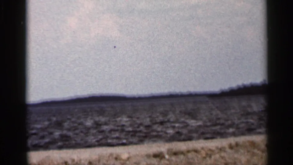 1966 Florida 8mm frame showing rippled open water, a low horizon, and bright sky with dark film-frame borders.