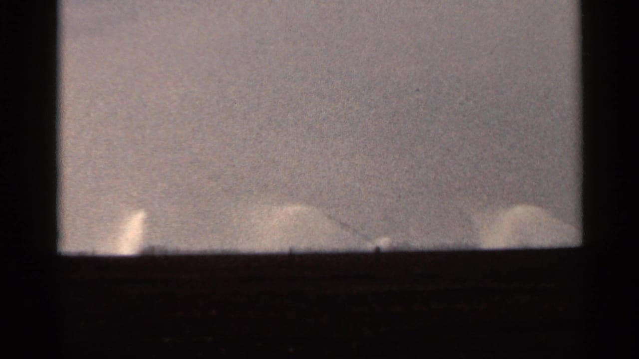 Final 1966 Florida 8mm frame with faint pale spray-like shapes along the horizon beneath a hazy, grainy sky.