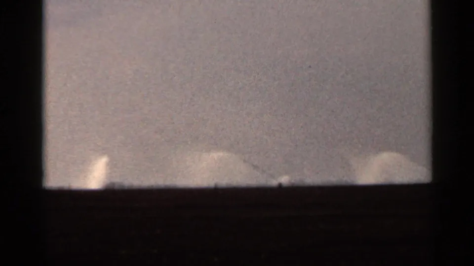 Final 1966 Florida 8mm frame with faint pale spray-like shapes along the horizon beneath a hazy, grainy sky.