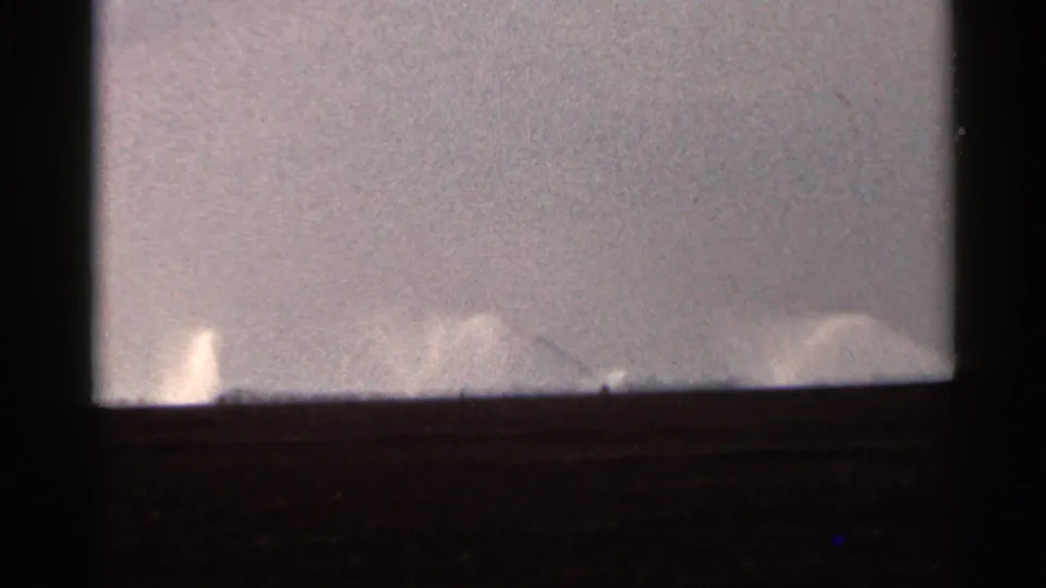 1966 Florida 8mm view of low, distant irrigation spray with dark frame edges and muted exposure.
