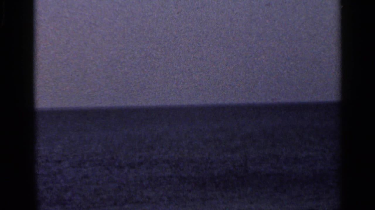 1966 Florida 8mm frame showing a distant ocean horizon, muted sky, dark gate edges, and soft film grain.