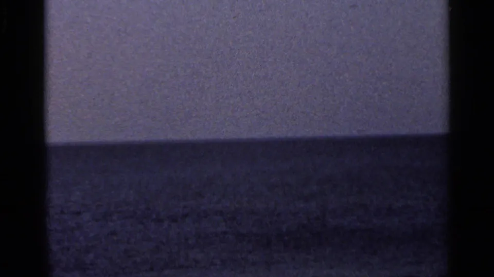 1966 Florida 8mm frame showing a distant ocean horizon, muted sky, dark gate edges, and soft film grain.