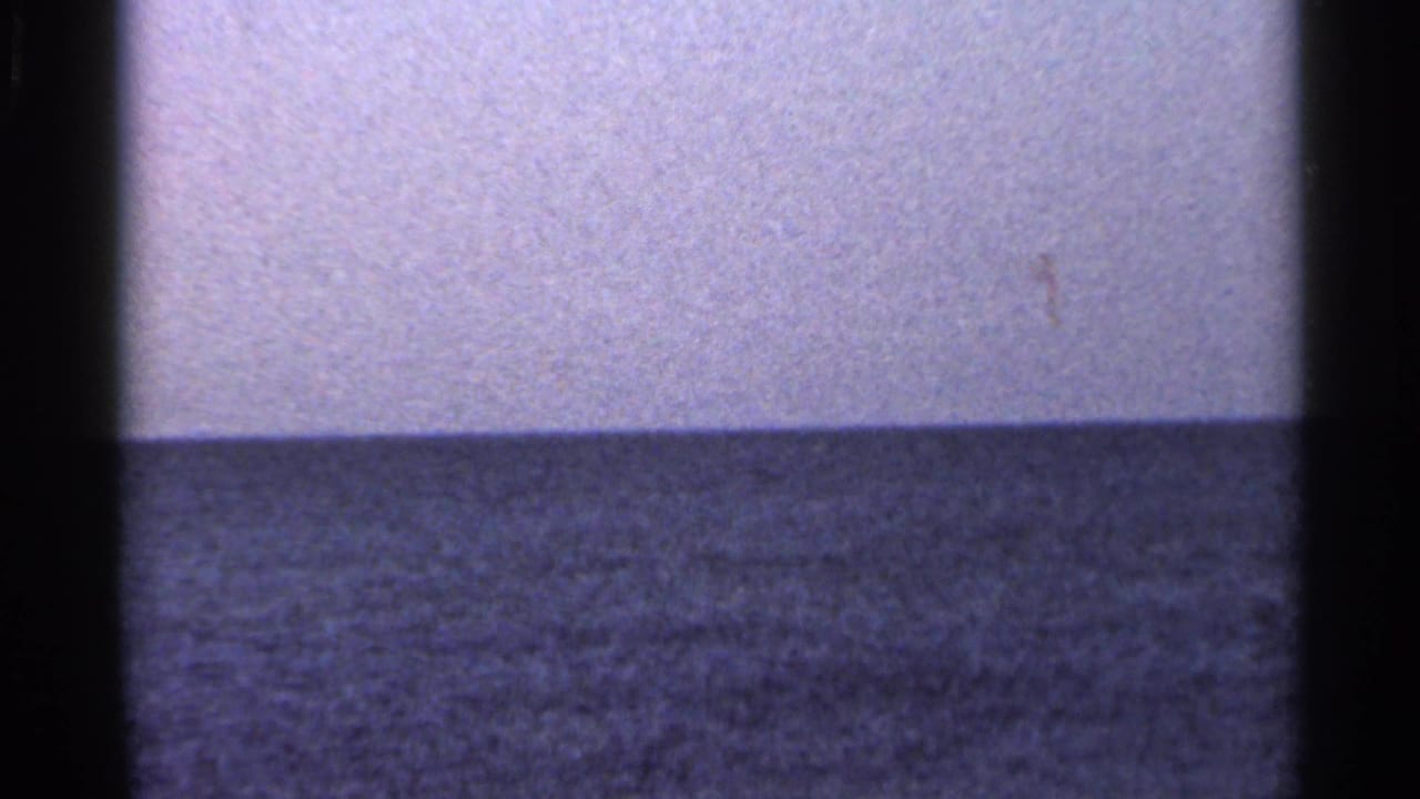 1966 Florida shoreline frame with rippled sea, pale sky, soft focus, and visible 8mm gate borders.