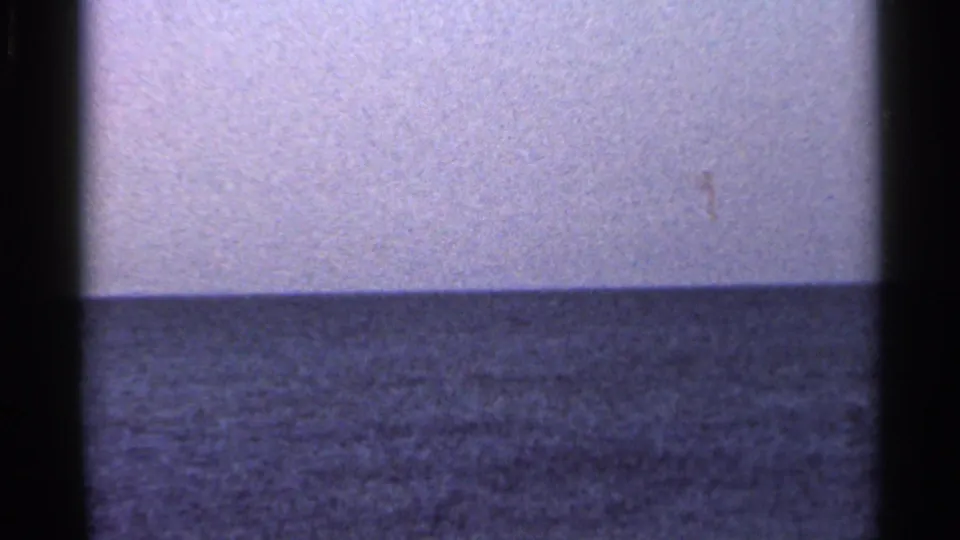 1966 Florida shoreline frame with rippled sea, pale sky, soft focus, and visible 8mm gate borders.