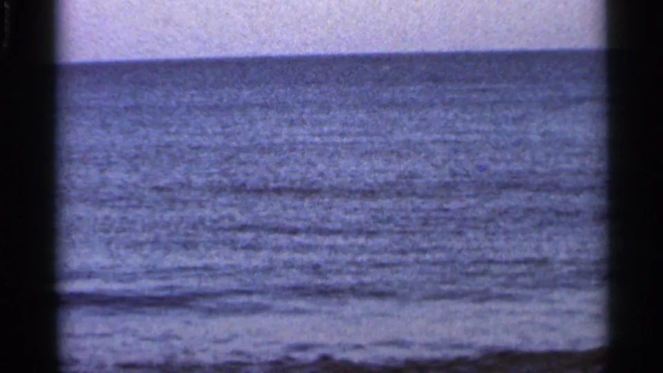 1966 Florida 8mm frame showing textured blue water, a low horizon, hazy sky, and visible film grain.