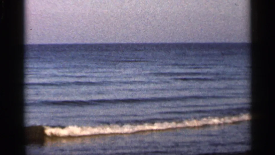 1966 Florida 8mm view of gentle surf washing onto a sandy beach, with ocean horizon and muted film color.