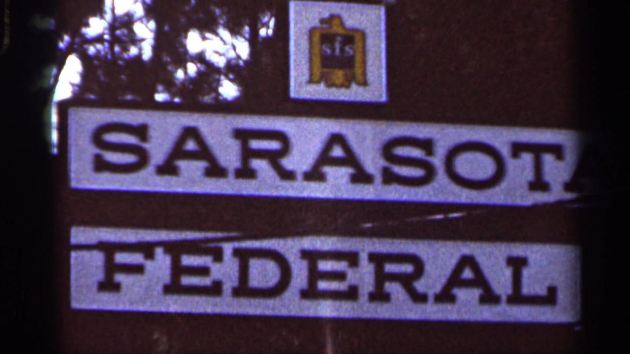 1966 8mm frame of the Sarasota Federal sign in Florida, with the SFS logo above and tree silhouettes in the background.