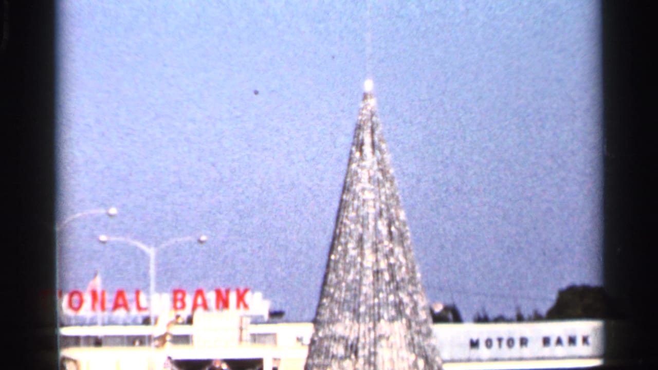 Tinseled Christmas tree in front of National Bank and Motor Bank signage.