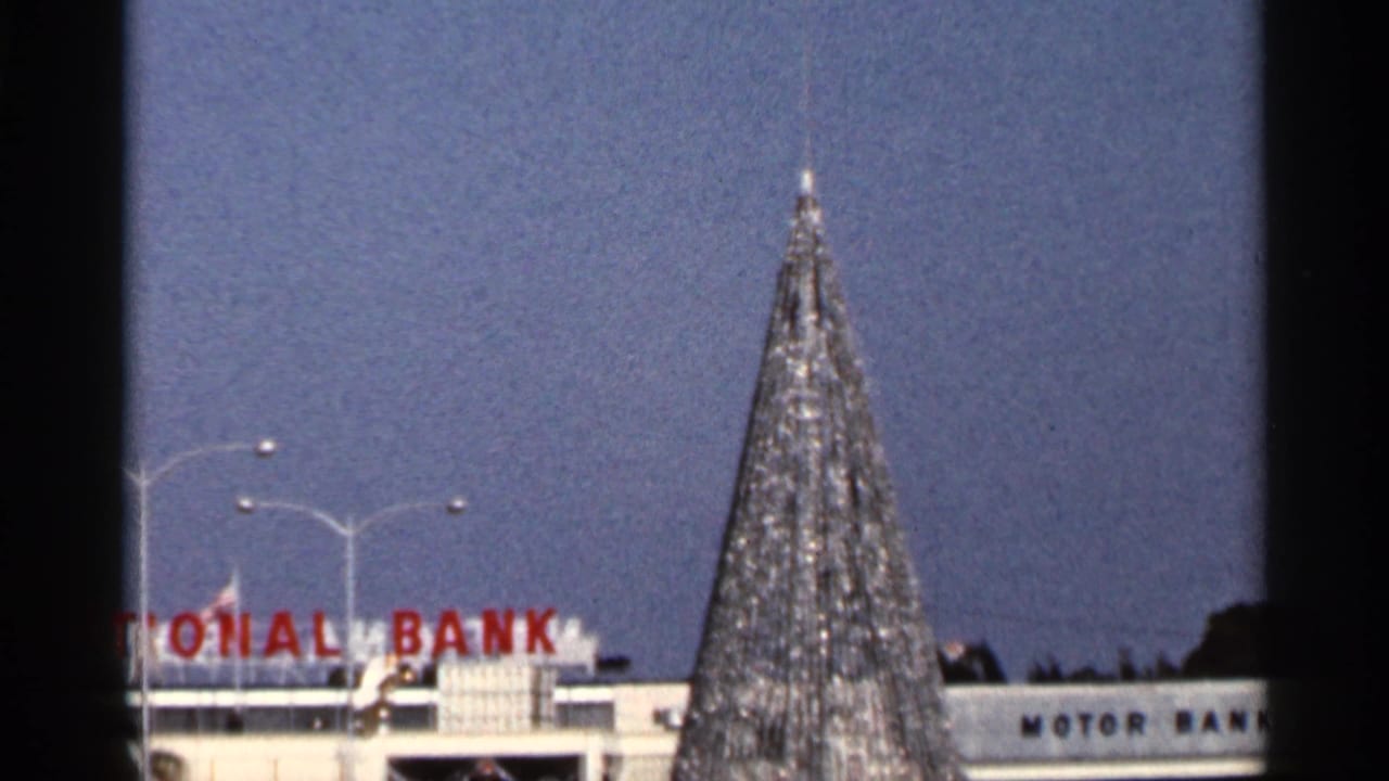 Christmas tree and partial National Bank sign seen from a moving vehicle.