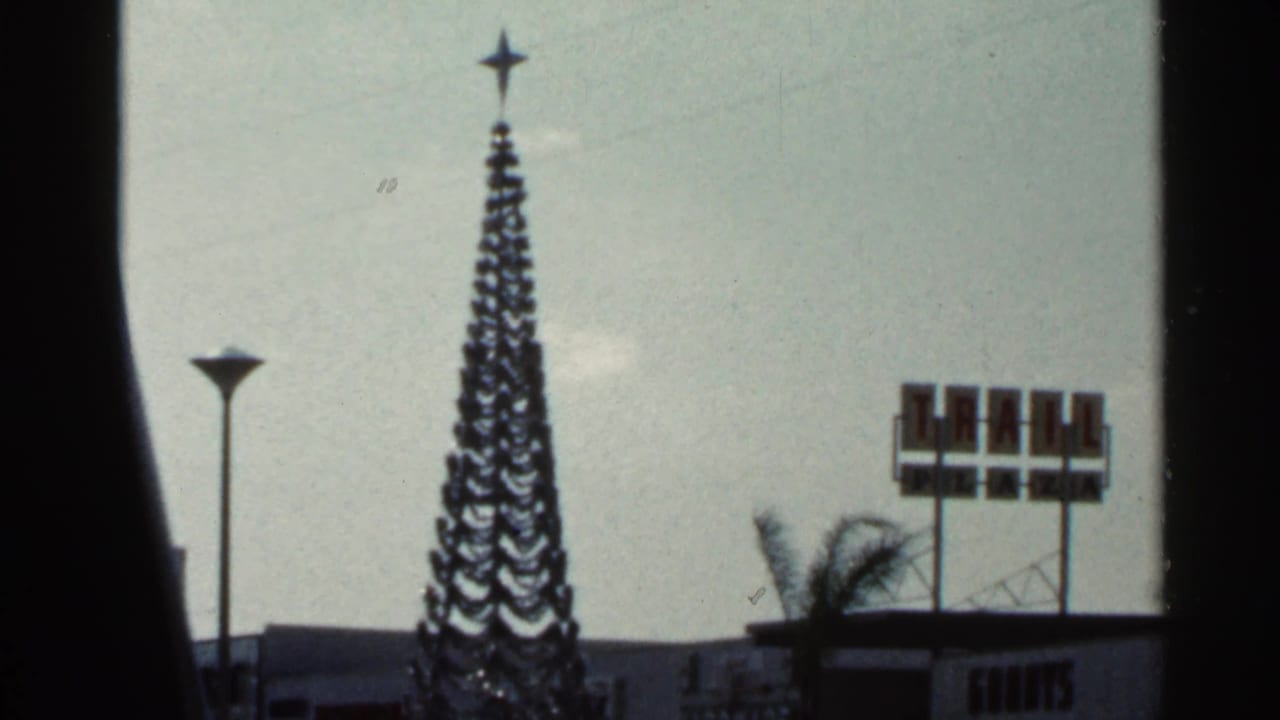 Final 1966 Florida frame showing a star-topped holiday tree beside partial bank signage and roadside commercial features.