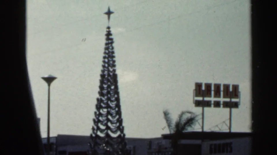 Final 1966 Florida frame showing a star-topped holiday tree beside partial bank signage and roadside commercial features.