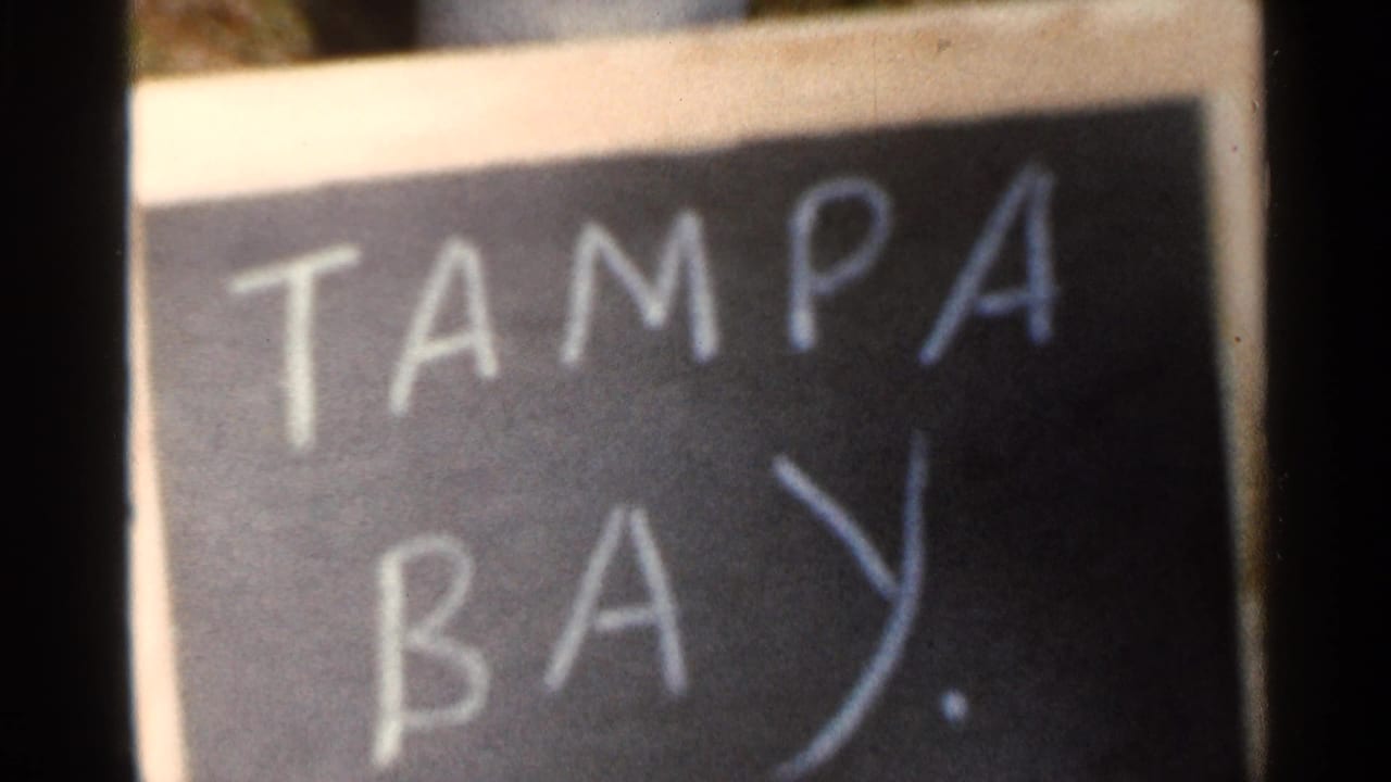 The Tampa Bay chalkboard title card appears closer, with soft focus and visible 8mm film texture.