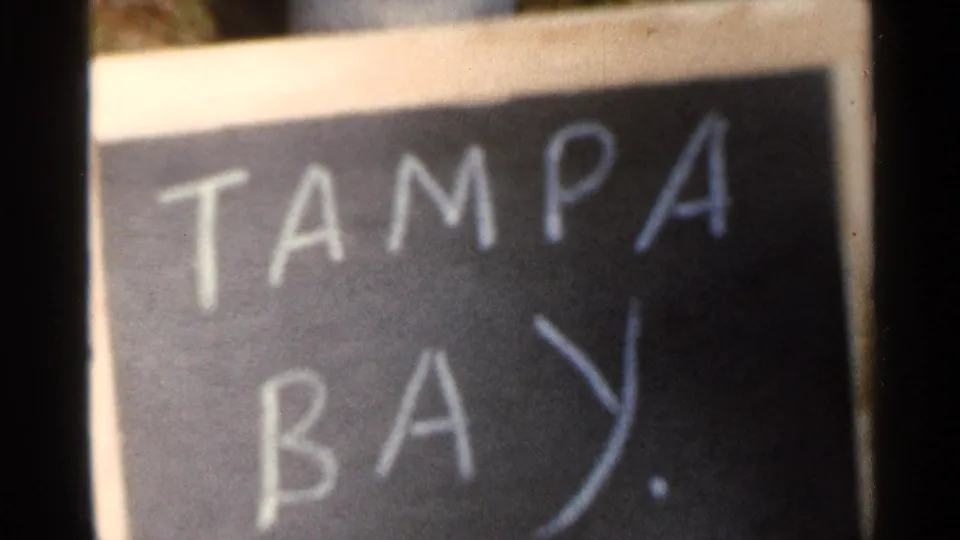 The Tampa Bay chalkboard title card appears closer, with soft focus and visible 8mm film texture.