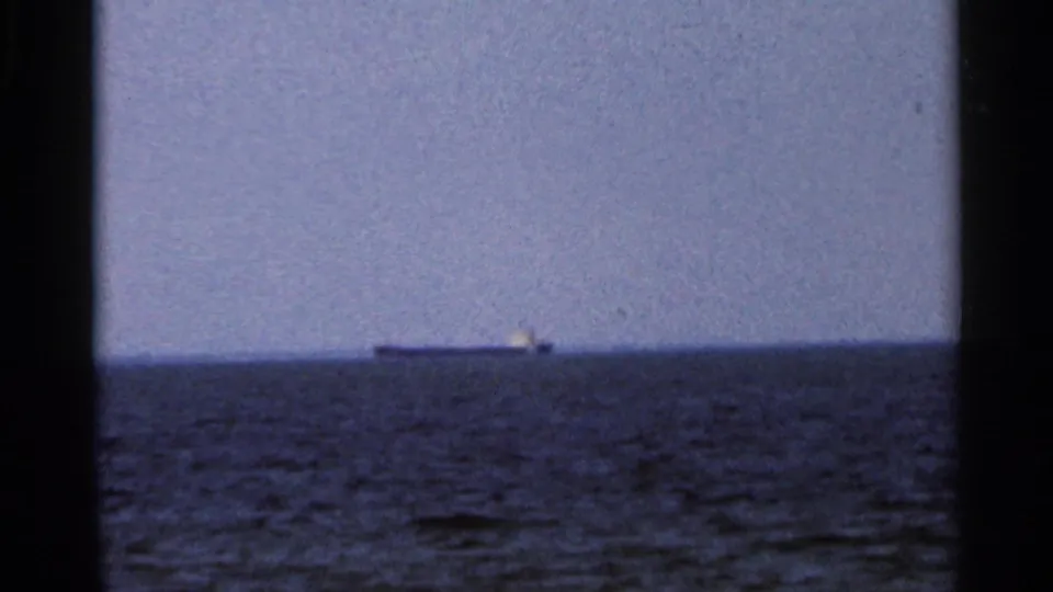 1966 Florida 8mm frame showing a distant ship low on the ocean horizon, seen through dark film gate borders.