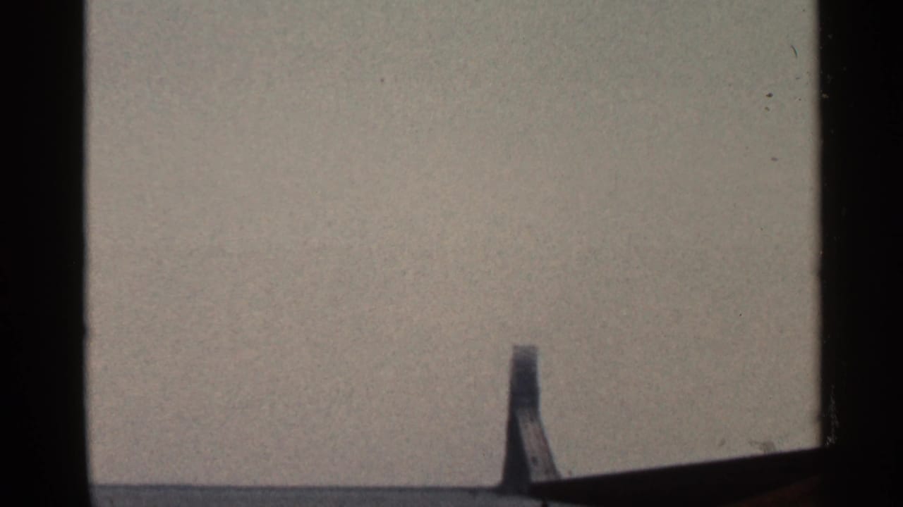Final 8mm frame appears mostly blank, with muted gray exposure, dark side borders, and a small partial shape along the lower edge.