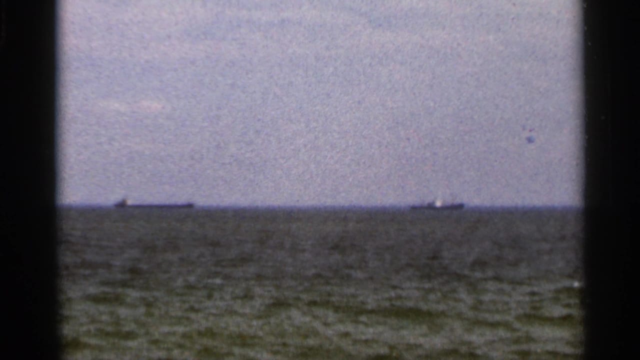 1966 Florida 8mm view of open water, low grey horizon, and two distant ships under a hazy coastal sky.