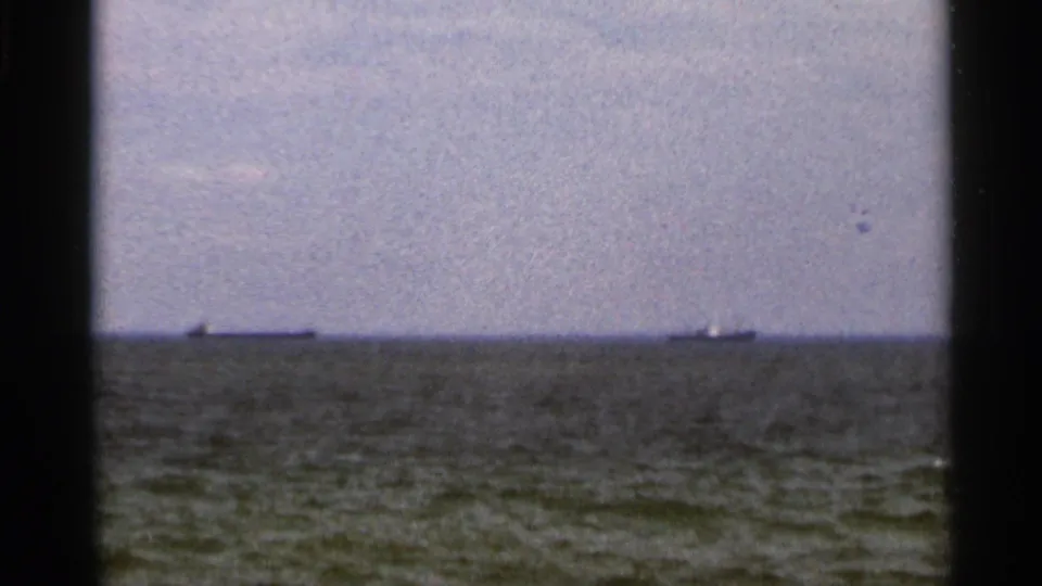 1966 Florida 8mm view of open water, low grey horizon, and two distant ships under a hazy coastal sky.