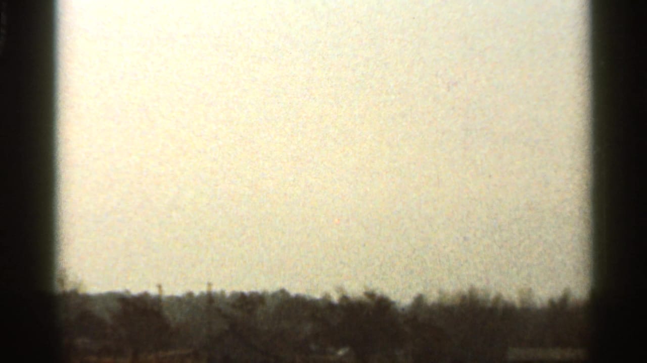 A 1966 Florida landscape frame shows a fading sky over distant trees and low structures, partly obscured by film edge shadow.