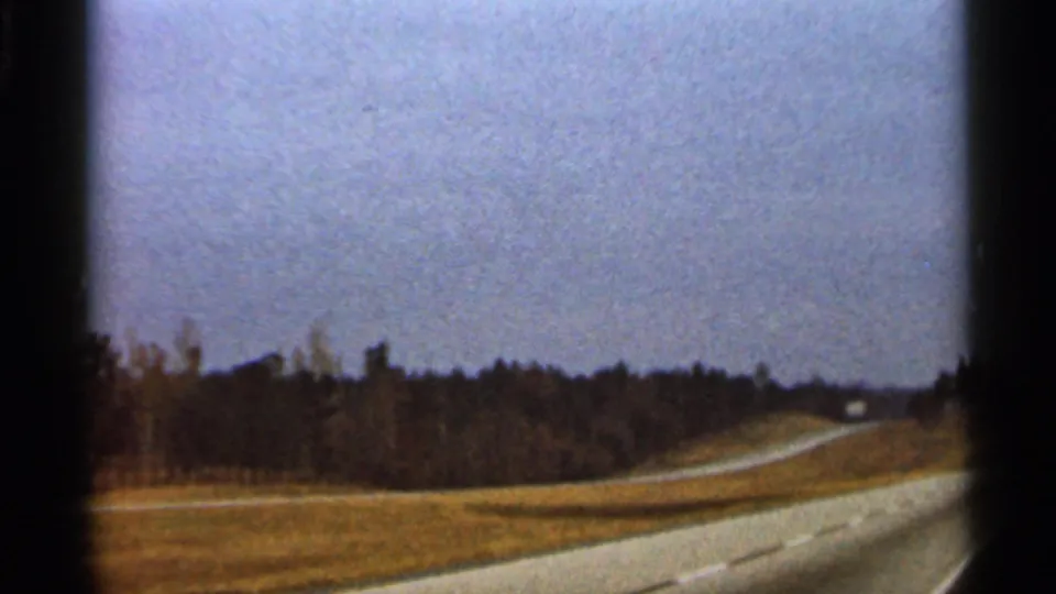 1966 Florida travel frame showing a pale winding road through open countryside with trees and a distant vehicle.