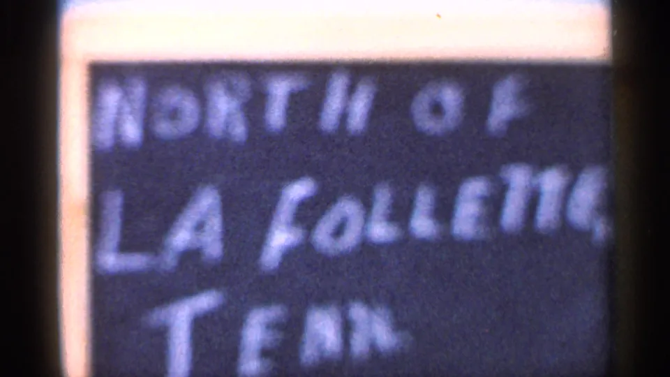 Close 8mm frame of a handwritten sign that appears to read North of La Follette, Tenn., filmed after the bus view.