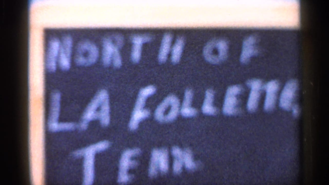 Final 1966 home-movie frame holding on the soft-focus handwritten North of La Follette, Tenn. sign.