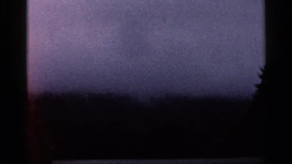 1966 Georgia 8mm view of a hazy mountain distance, dark tree line, and vehicle-window edge during road travel.