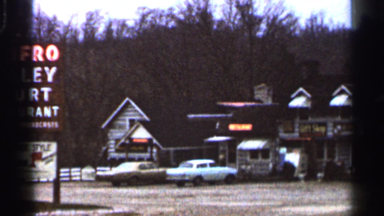 The 1966 Georgia home-movie frame widens to show the Renfro Valley Court Restaurant sign beside low roadside buildings and parked cars.