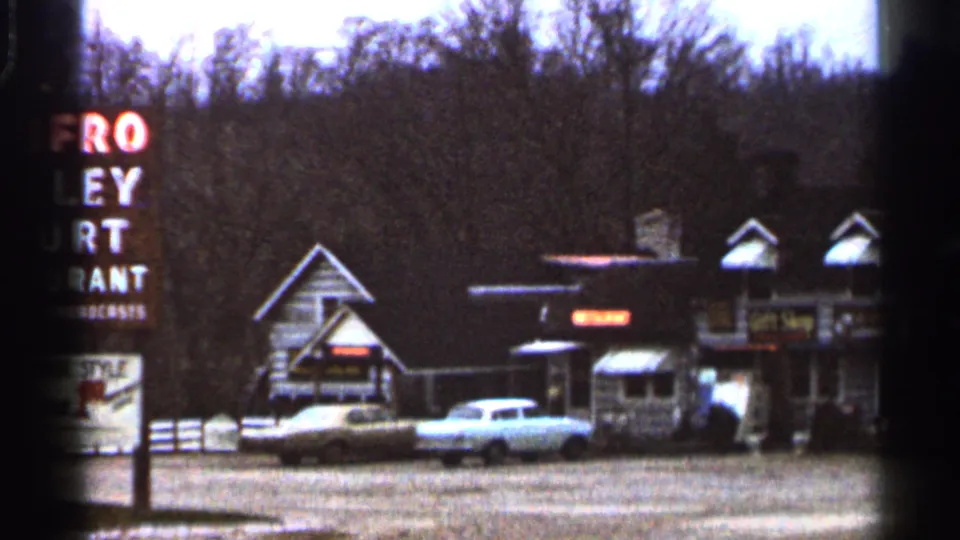 The 1966 Georgia home-movie frame widens to show the Renfro Valley Court Restaurant sign beside low roadside buildings and parked cars.