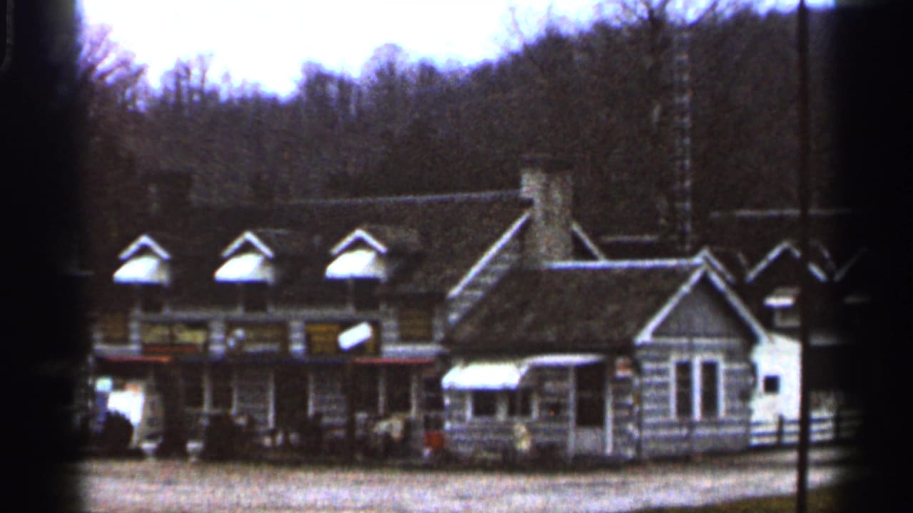 Closer view of the rustic building row with storefront signs, dormer windows, and a small attached structure.