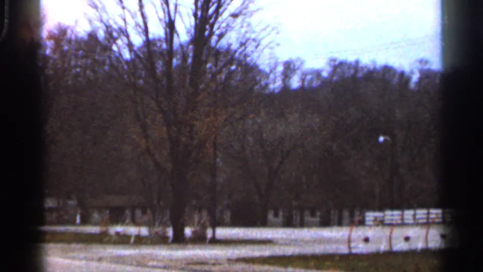 1966 Georgia landscape frame showing leafless trees, open grass, a low fence, and wooded hills in soft 8mm color.