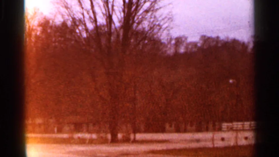 1966 Georgia home-movie frame with orange color shift over bare trees, open land, and a low fence line.
